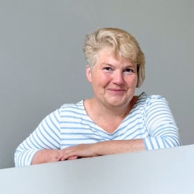 Porträt von Susanne Krüger, mit den Armen auf einer Mauer lehnend